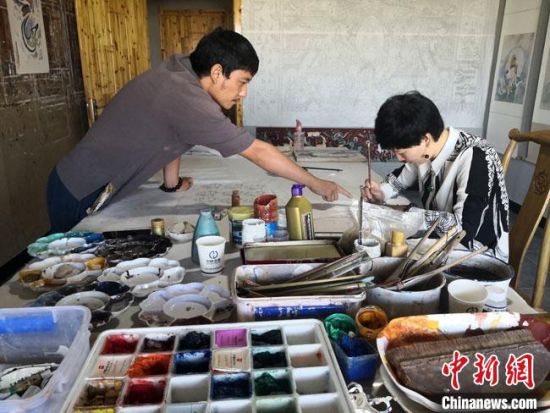 圖為2020年8月下旬，敦煌“80后”畫家張杰龍(左)在為云南麗江“學(xué)生”莫北講解敦煌壁畫的繪畫技巧?！●T志軍 攝