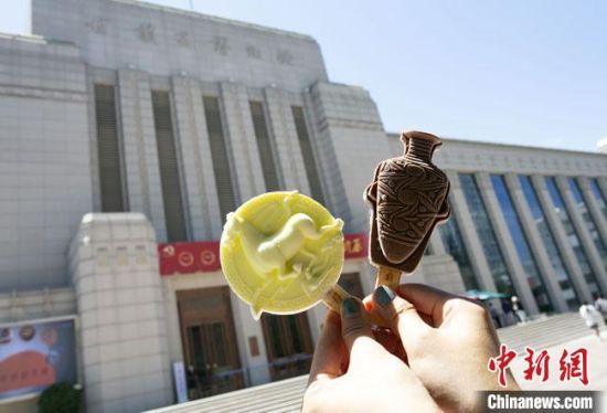 2021年7月30日，游客手拿“銅奔馬”“彩陶瓶”造型的雪糕，在甘肅省博物館前拍照打卡?！「哒?攝