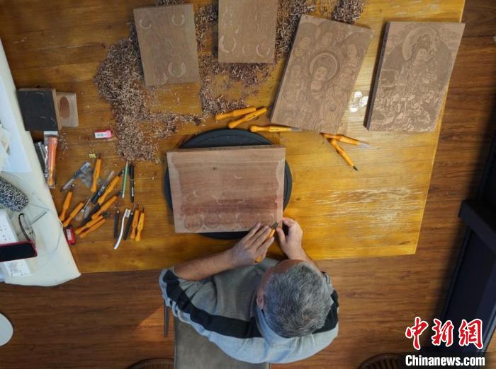 圖為徐晉林正在梨木木板上雕刻敦煌壁畫(huà)?！【琶赖┰?　攝