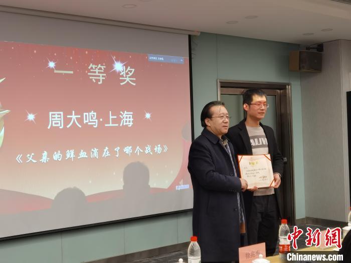 圖為作家、西北師范大學(xué)新聞與傳媒學(xué)院院長徐兆壽頒發(fā)一等獎證書，代領(lǐng)獎?wù)呱吓_領(lǐng)獎。　楊娜 攝