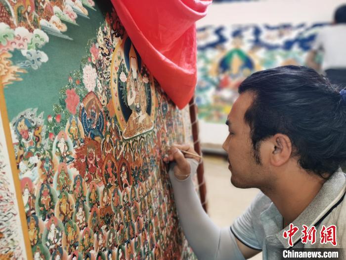 圖為更登才讓的徒弟繪畫(huà)唐卡?！?zhí)砀?攝
