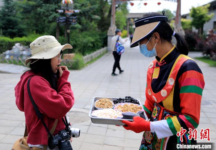 圖為身穿土族服飾的女性介紹當?shù)靥厣〕??！⊙Φ?攝