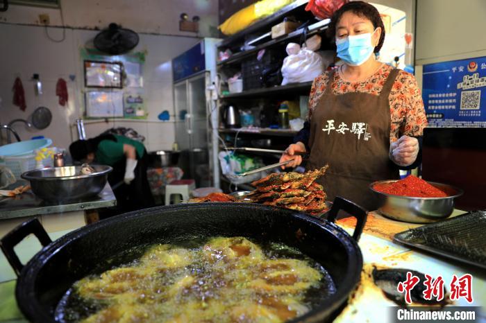 圖為平安驛·河湟民俗文化體驗(yàn)地內(nèi)的商戶炸干板魚。　薛蒂 攝