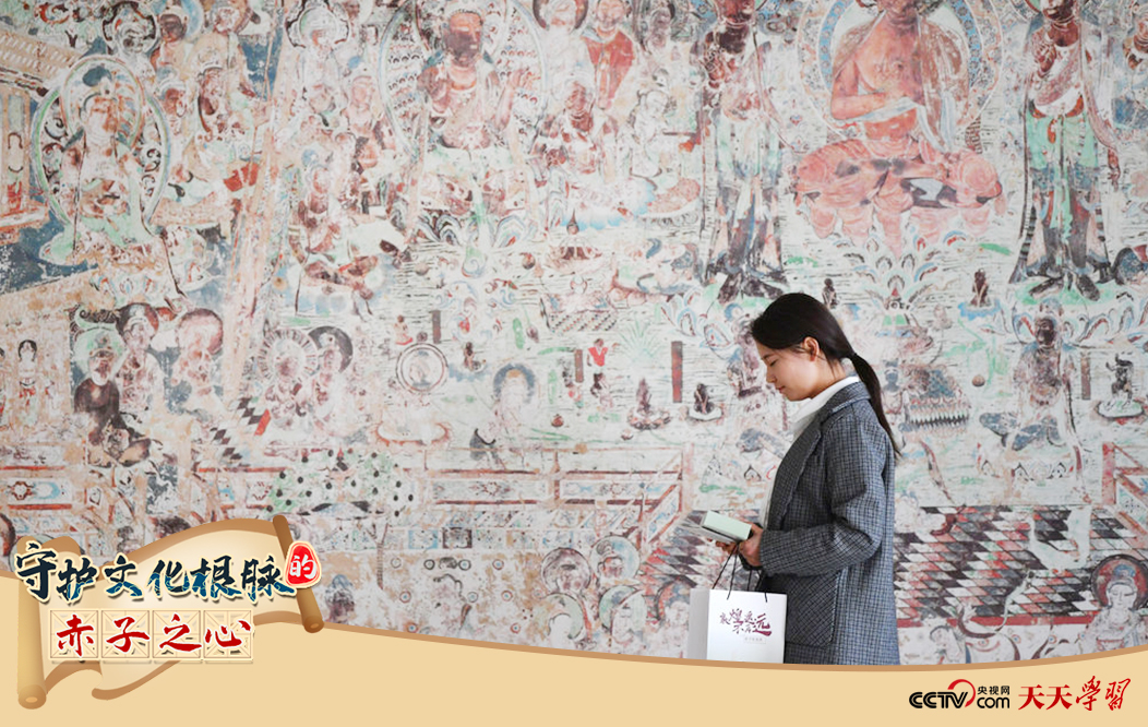 2023年4月25日，敦煌研究院文物數(shù)字化保護團隊創(chuàng)意營銷人員廖雪婷從一幅高保真復(fù)制壁畫前走過。