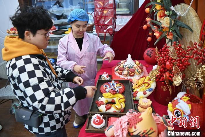 1月25日，隨著春節(jié)臨近，蘭州一花饃店“龍”元素花饃熱銷。圖為工作人員向顧客推薦“龍”元素花饃。九美旦增 攝</p><p>