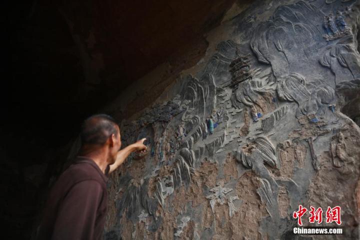 7月15日，甘肅省平?jīng)鍪袥艽h百里石窟長(zhǎng)廊羅漢洞石窟內(nèi)，該窟文保員郭建平介紹窟內(nèi)石刻彩繪壁畫(huà)。郭建平家中三代人曾自發(fā)保護(hù)羅漢洞石窟。羅漢洞石窟遺存40余個(gè)窟龕，以北魏至清代風(fēng)格為主。中新社記者 李亞龍 攝