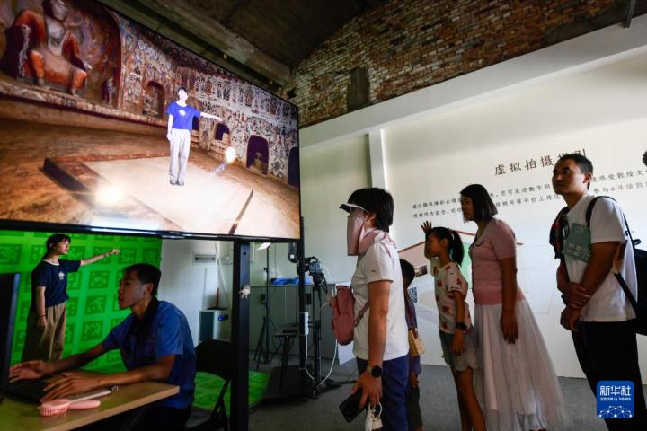 7月22日，游客體驗(yàn)“尋境敦煌——數(shù)字敦煌沉浸展”后，在虛擬演播廳拍攝一段真人與洞窟虛擬場景交互的視頻。新華社記者 郎兵兵 攝</p>
<p>