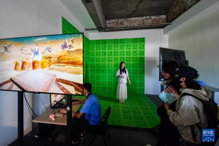7月22日，游客體驗(yàn)“尋境敦煌——數(shù)字敦煌沉浸展”后，在虛擬演播廳拍攝一段真人與洞窟虛擬場景交互的視頻。新華社記者 郎兵兵 攝</p>
<p>